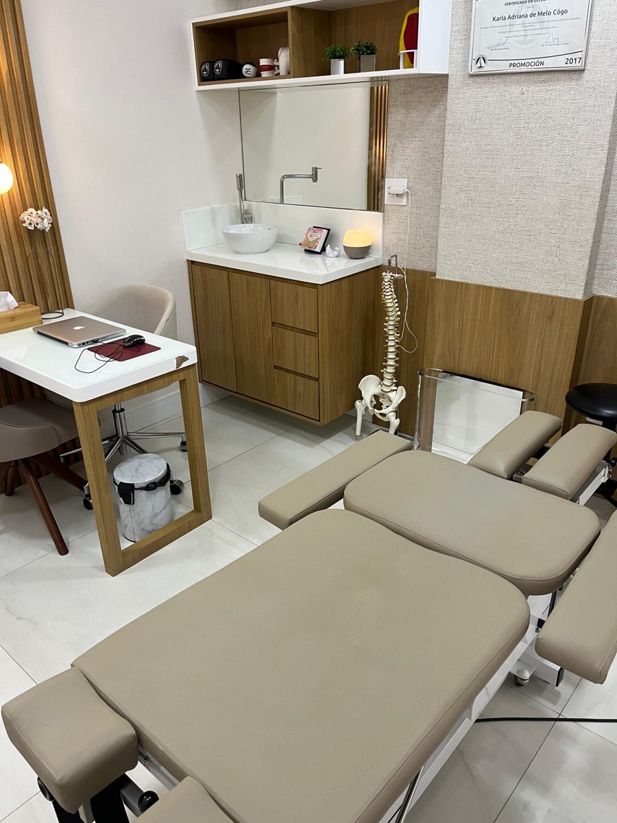 Sala de avaliação com maca, coluna anatômica e diploma de osteopatia